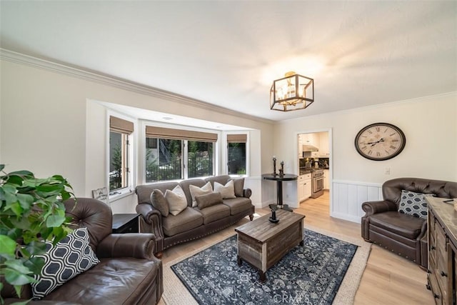 living room featuring light hardwood / wood-style flooring, ornamental molding, and a notable chandelier