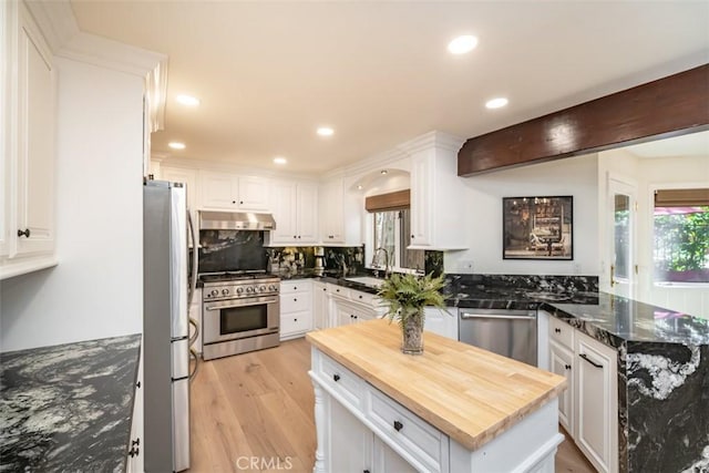 kitchen with butcher block counters, white cabinets, sink, light hardwood / wood-style flooring, and stainless steel appliances