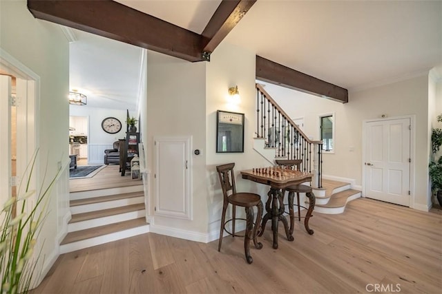 dining room featuring light wood-type flooring and beamed ceiling