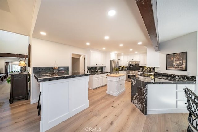 kitchen featuring white cabinetry, stainless steel appliances, kitchen peninsula, and beamed ceiling