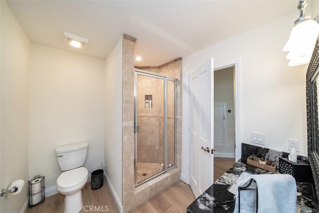 bathroom with hardwood / wood-style flooring, an enclosed shower, and toilet