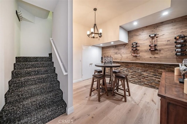 interior space featuring light hardwood / wood-style flooring, wood walls, and a notable chandelier