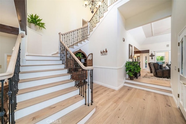 stairway with hardwood / wood-style floors, lofted ceiling with beams, and an inviting chandelier