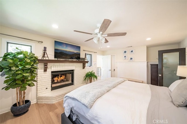 bedroom featuring ceiling fan, light hardwood / wood-style flooring, and a fireplace