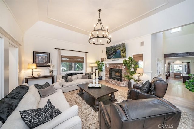 living room featuring a fireplace, plenty of natural light, a tray ceiling, and an inviting chandelier