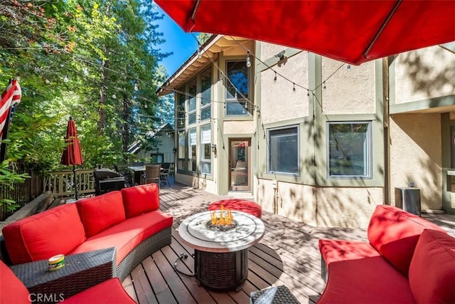 wooden terrace with an outdoor living space with a fire pit