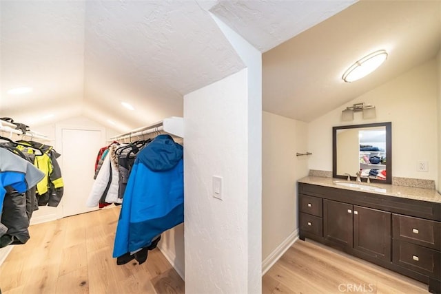 bathroom with hardwood / wood-style flooring, vanity, and vaulted ceiling