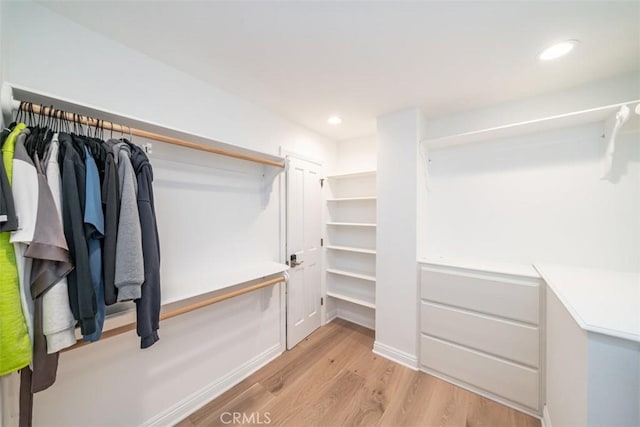 walk in closet with light hardwood / wood-style flooring