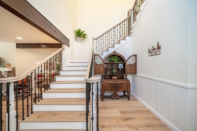 stairway with hardwood / wood-style flooring and beam ceiling