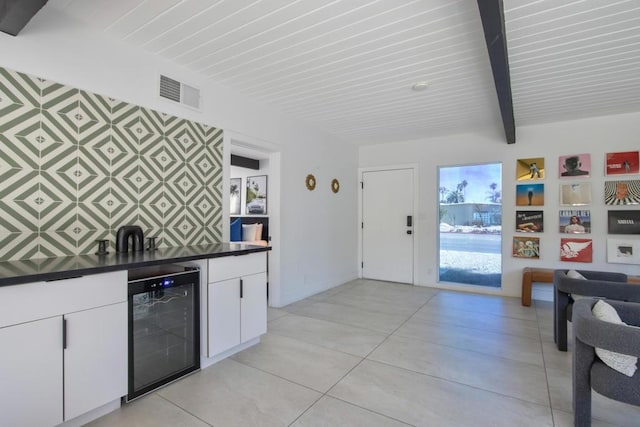 kitchen featuring wine cooler, white cabinets, and beamed ceiling