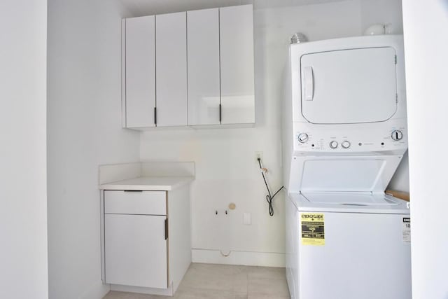 laundry area with cabinets, stacked washer / dryer, and light tile patterned floors