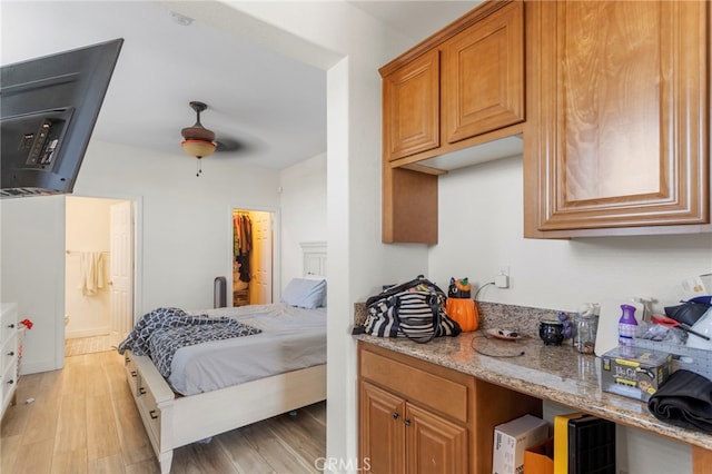 bedroom with ceiling fan, a spacious closet, connected bathroom, and light hardwood / wood-style flooring