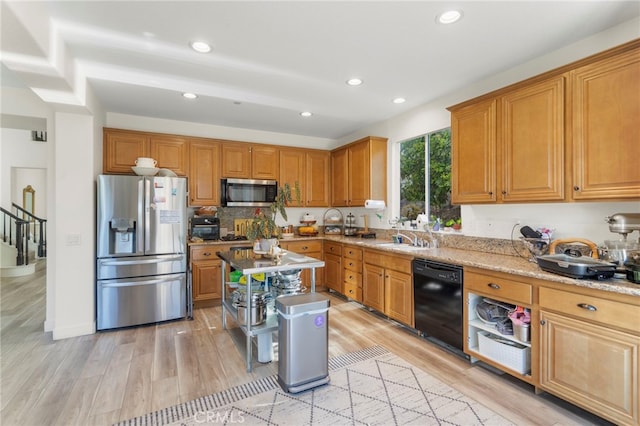 kitchen with light wood-type flooring, light stone countertops, sink, and stainless steel appliances