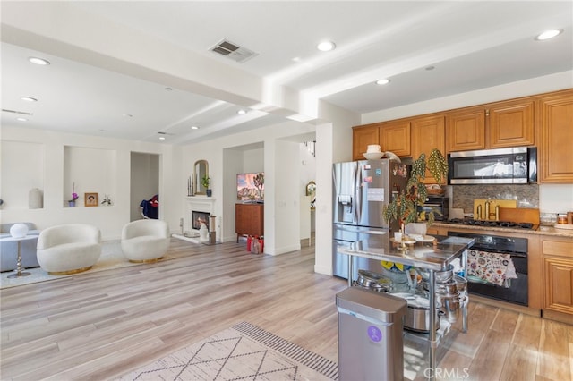 kitchen with light hardwood / wood-style floors, backsplash, black appliances, and beamed ceiling