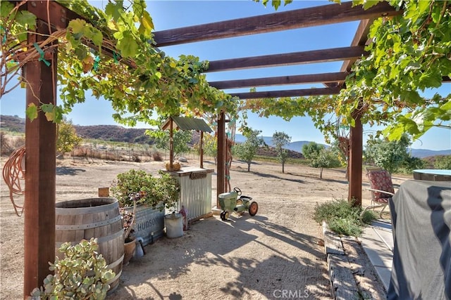 view of patio / terrace featuring a rural view, a pergola, a mountain view, and area for grilling