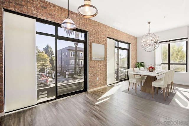 unfurnished dining area featuring light hardwood / wood-style floors, brick wall, and an inviting chandelier