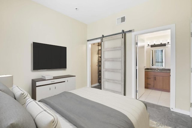 tiled bedroom featuring a barn door, sink, and connected bathroom