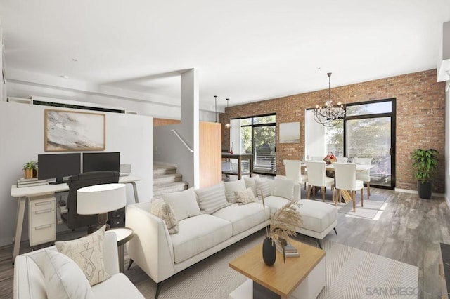 living room with brick wall, hardwood / wood-style floors, and a notable chandelier