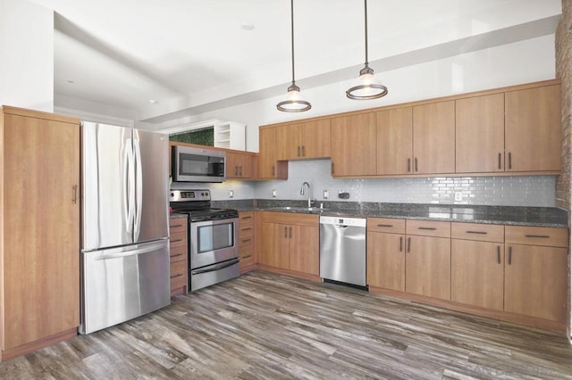 kitchen featuring dark stone countertops, sink, hanging light fixtures, appliances with stainless steel finishes, and dark wood-type flooring