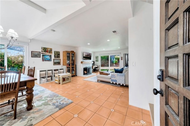 tiled living room with a fireplace, beamed ceiling, and a healthy amount of sunlight