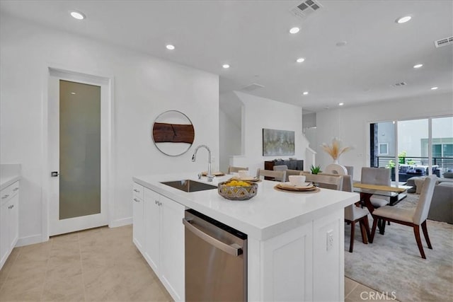 kitchen featuring light tile patterned floors, a kitchen island with sink, stainless steel dishwasher, white cabinets, and sink