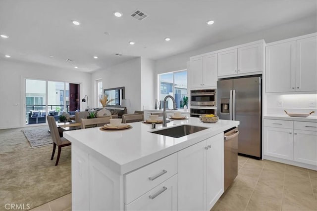 kitchen with sink, appliances with stainless steel finishes, an island with sink, plenty of natural light, and white cabinets