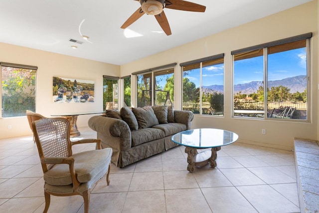 living room featuring ceiling fan, light tile patterned floors, a healthy amount of sunlight, and a mountain view