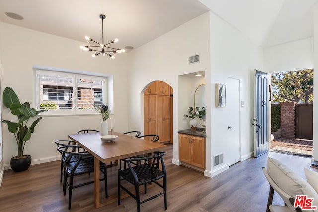 dining space featuring dark hardwood / wood-style flooring, a chandelier, and high vaulted ceiling