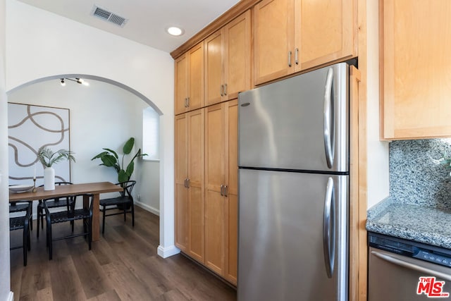 kitchen with dark wood-type flooring, appliances with stainless steel finishes, backsplash, and light stone countertops