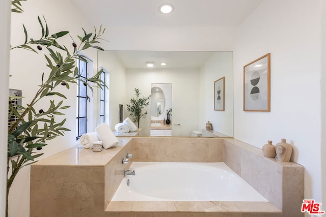 bathroom with tiled tub and toilet