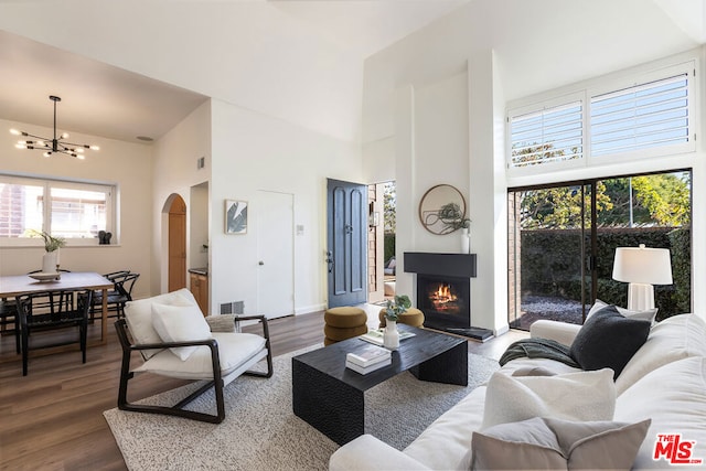 living room featuring a towering ceiling, hardwood / wood-style floors, a chandelier, and a fireplace