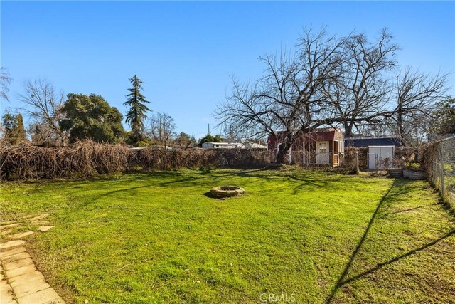 view of yard with an outdoor fire pit and a storage unit