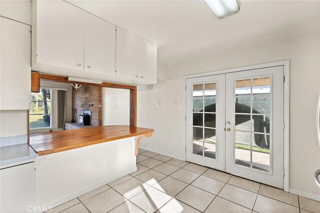 kitchen with plenty of natural light, light tile patterned floors, white cabinets, and french doors