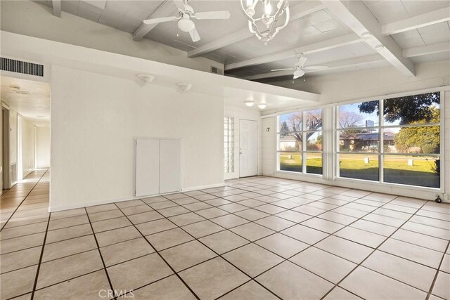 empty room with ceiling fan with notable chandelier, light tile patterned floors, and beamed ceiling