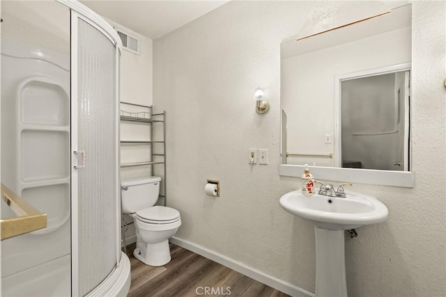 bathroom featuring toilet, wood-type flooring, and an enclosed shower