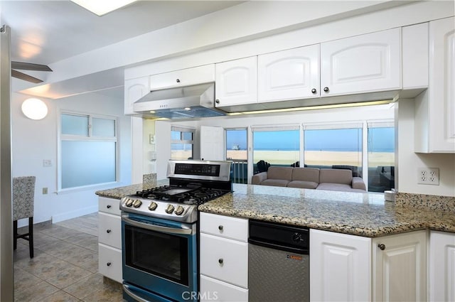 kitchen with ventilation hood, stainless steel gas stove, light stone counters, and white cabinetry