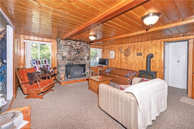 living room featuring a wood stove, carpet, wood walls, and beamed ceiling