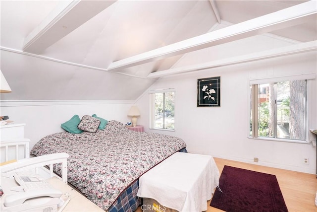 bedroom featuring light wood-type flooring and vaulted ceiling with beams