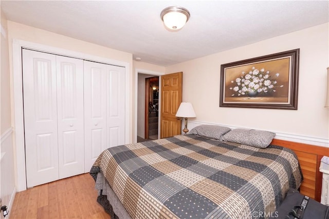 bedroom with light wood-type flooring, a closet, and wooden walls