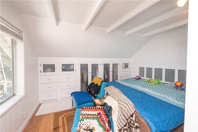 bedroom featuring lofted ceiling with beams, multiple windows, and hardwood / wood-style flooring