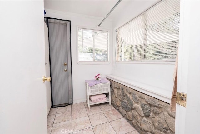 doorway to outside with light tile patterned floors and crown molding