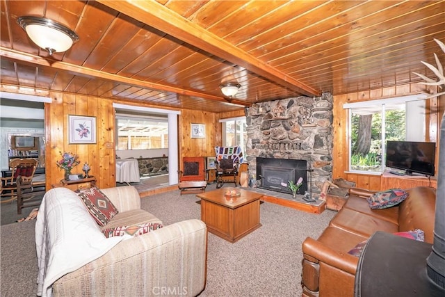 carpeted living room with beam ceiling, wood walls, and a fireplace