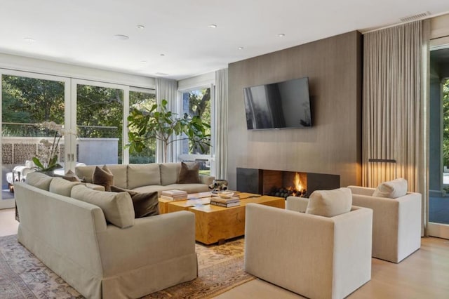 living room featuring light wood-type flooring and a large fireplace