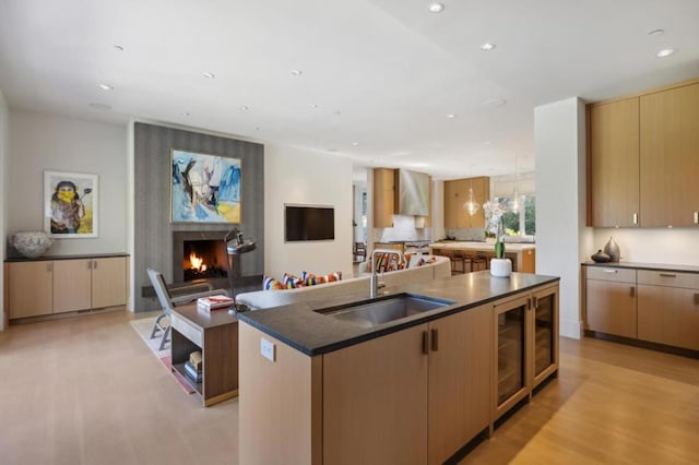 kitchen with a kitchen island with sink, sink, light brown cabinetry, and light hardwood / wood-style floors