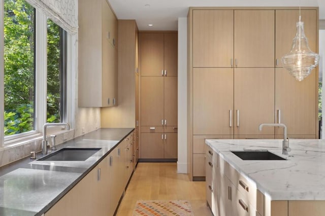 kitchen featuring decorative light fixtures, sink, light brown cabinetry, and dark stone countertops