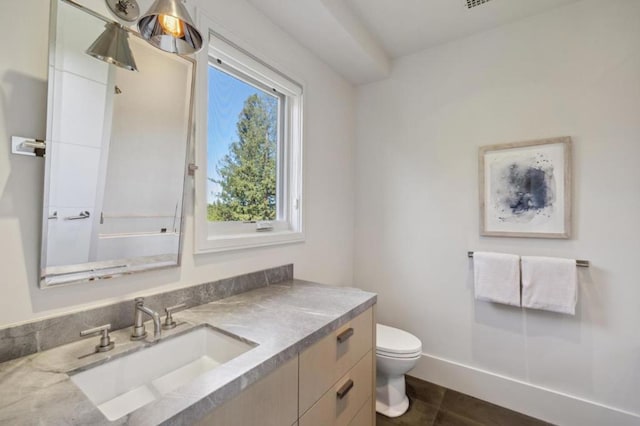 bathroom with toilet, vanity, and tile patterned floors