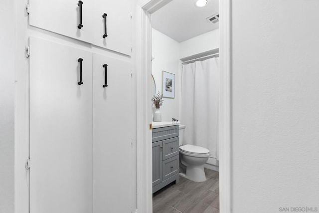 bathroom with toilet, vanity, and walk in shower