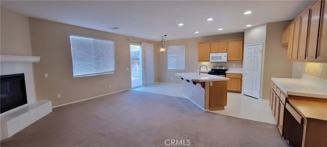 kitchen with light colored carpet, a center island with sink, a kitchen bar, hanging light fixtures, and stainless steel range