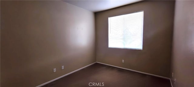 spare room featuring dark colored carpet