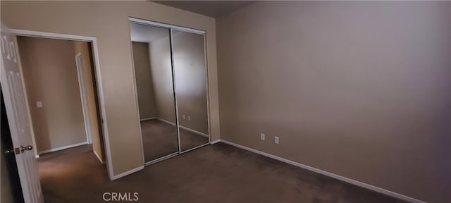 unfurnished bedroom featuring a closet and dark carpet